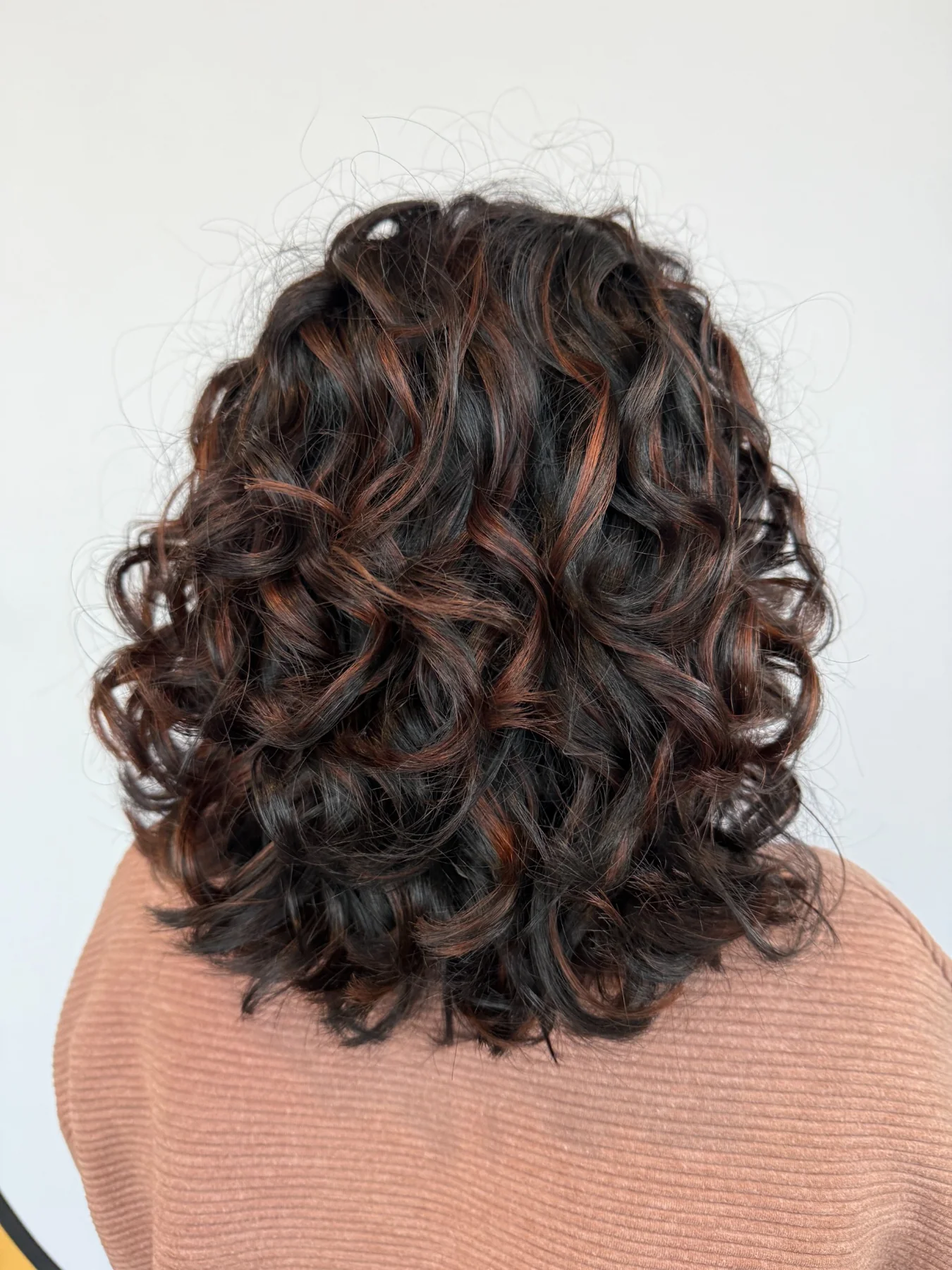 Soft copper dimension through shoulder-length brunette curls